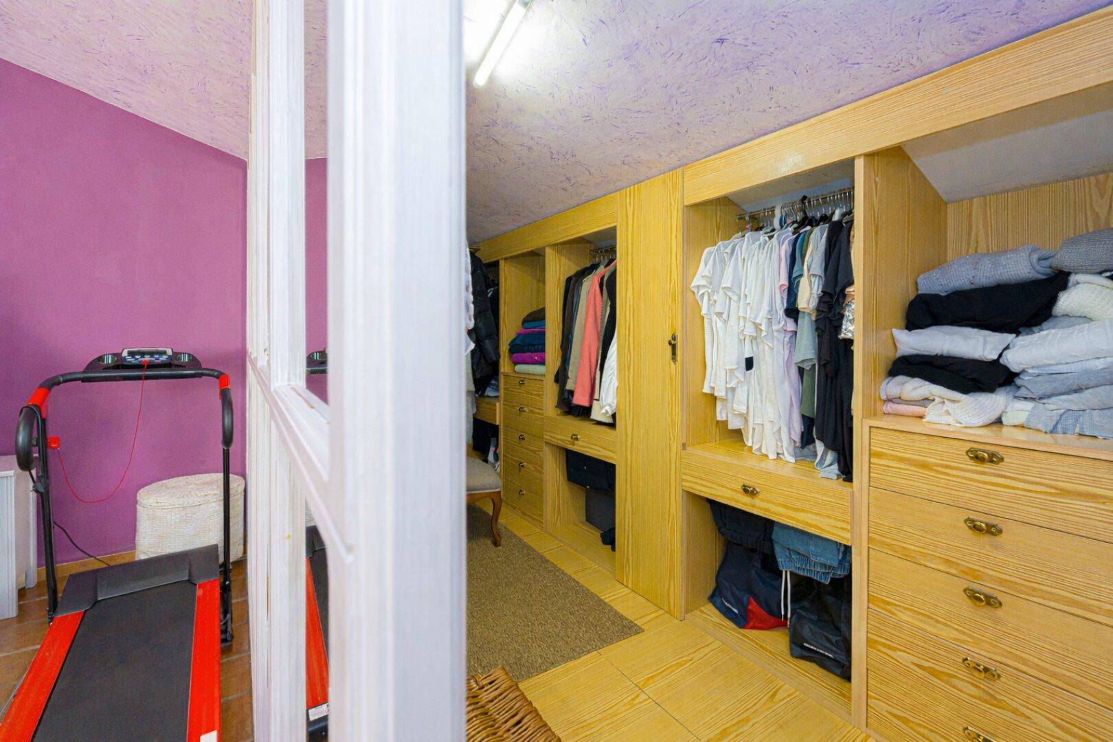 Begehbarer Kleiderschrank im Dachgeschoss mit maßgefertigten Holzschränken und Stauraum.