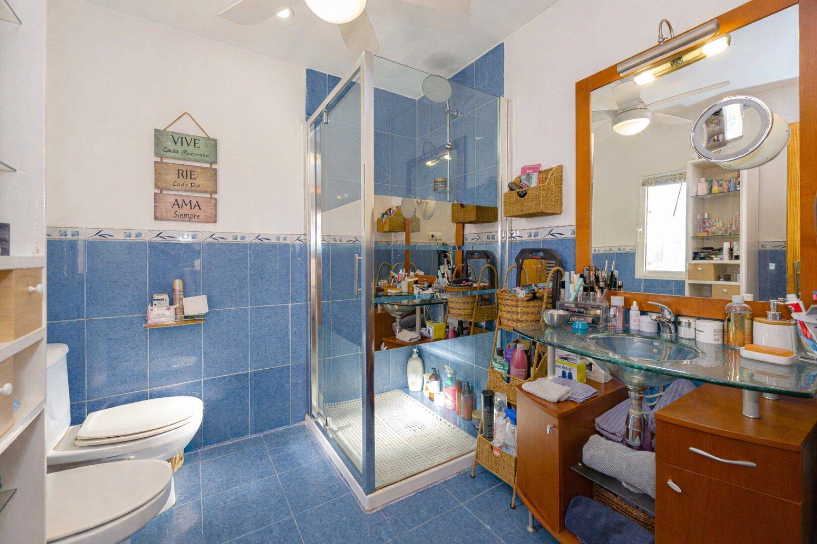 Modernes Badezimmer mit blauen Fliesen, Dusche und großem Spiegel.