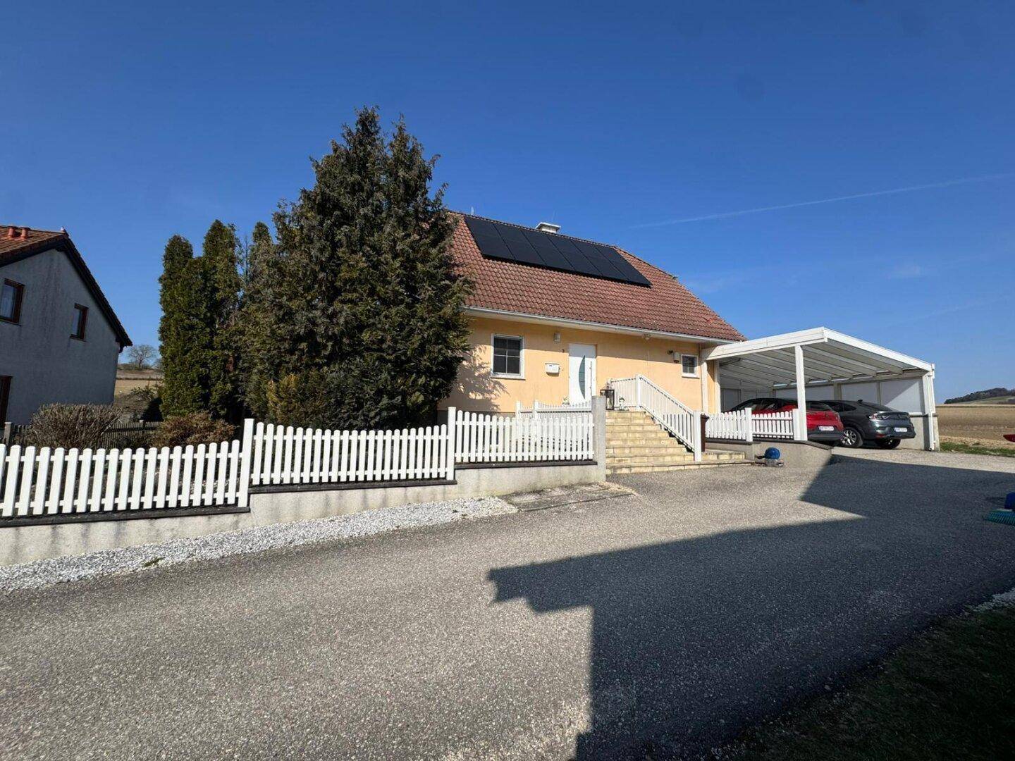 Ansicht des Hauses mit Carport, Photovoltaikanlage und gepflegtem Vorgarten in sonniger Lage.