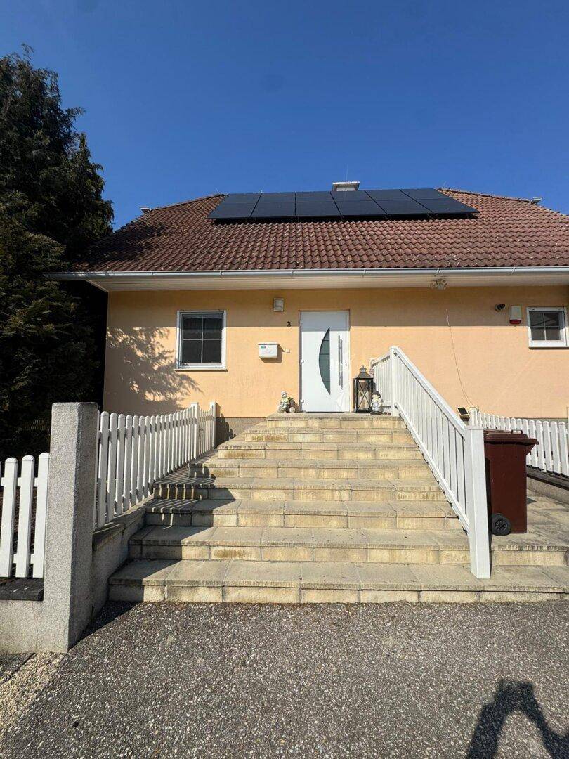 Detailansicht des Hauseingangs mit Photovoltaikanlage auf dem Ziegeldach.
