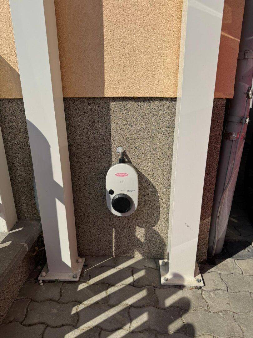 Eine Ladestation für Elektrofahrzeuge ist an der Hauswand neben dem Carport installiert.