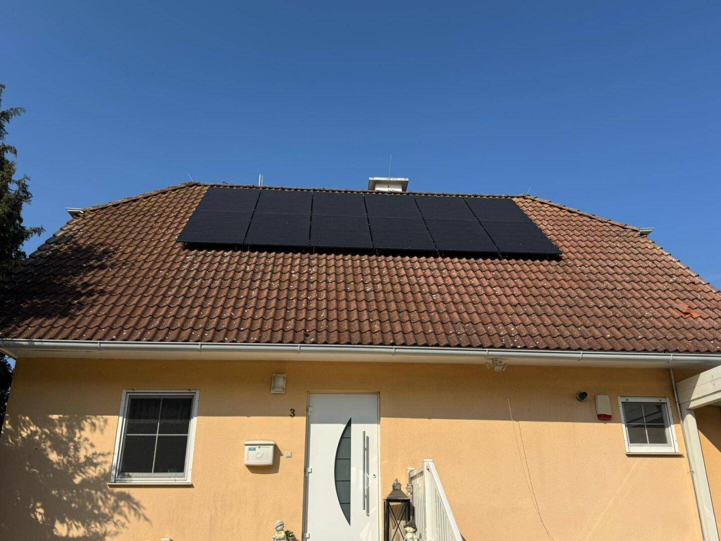 Das Haus mit einem großen Array von Photovoltaikmodulen auf dem Ziegeldach.