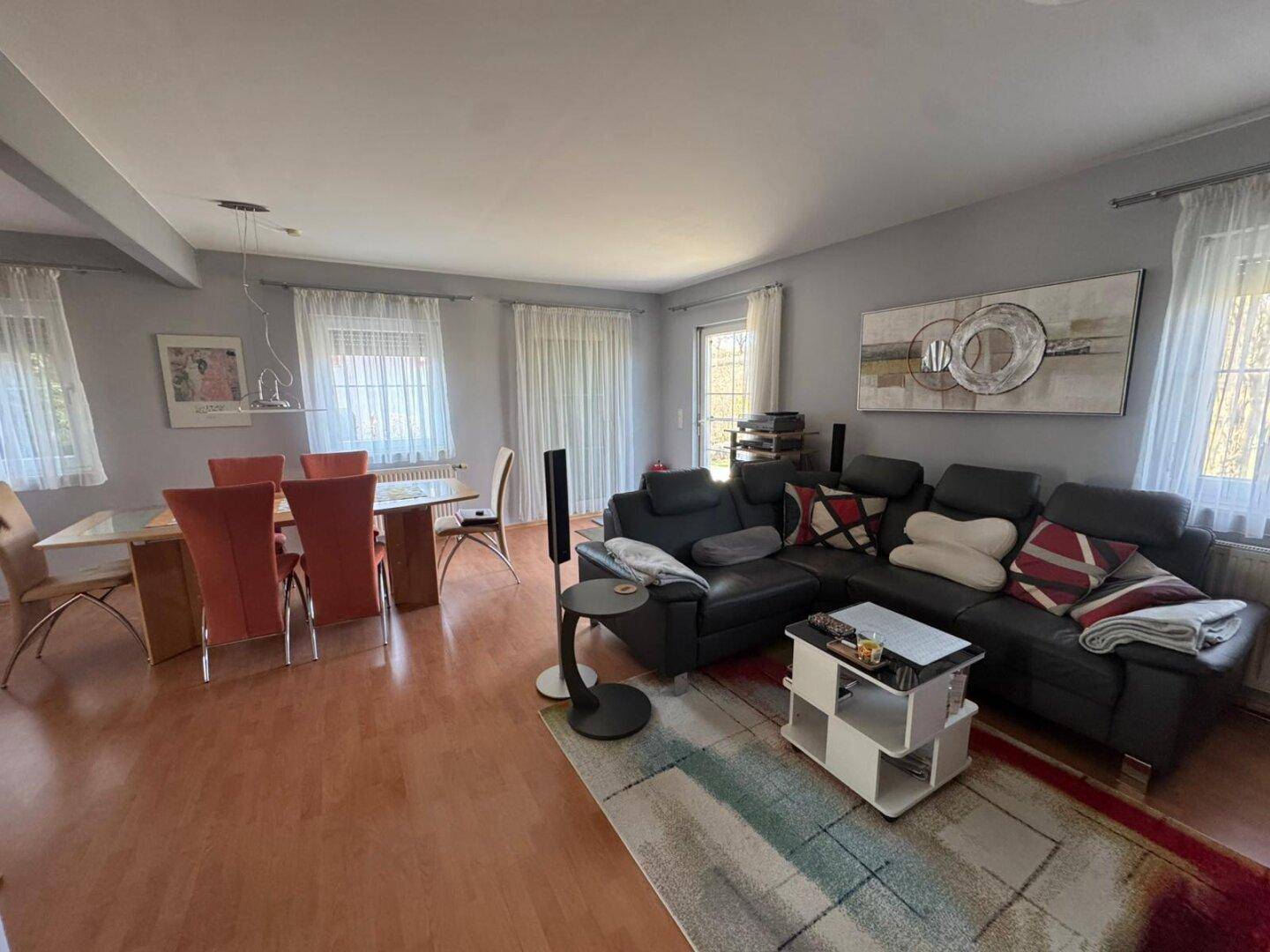 Geräumiger Wohn-Essbereich mit großem Sofa, Esstisch und Laminatboden.