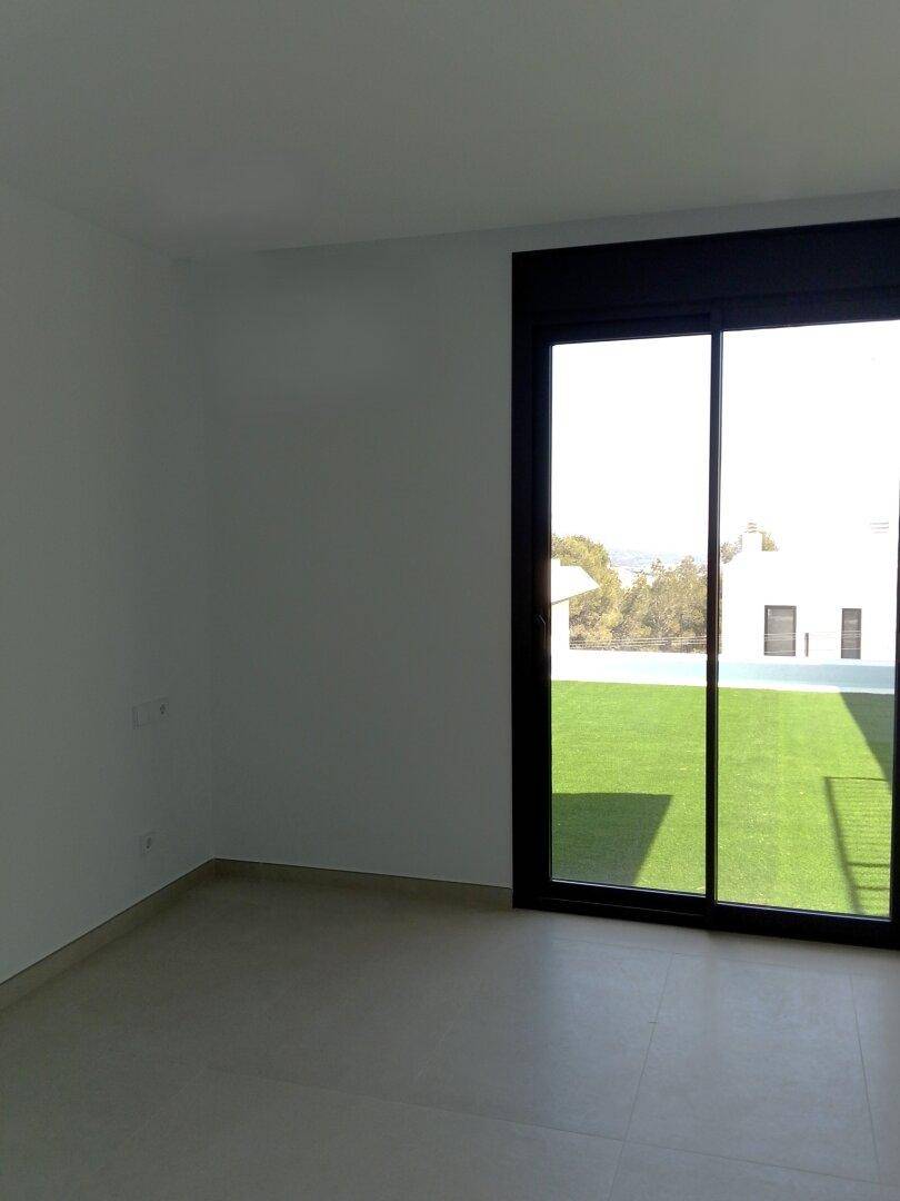 Schlafzimmer mit großen Schiebetüren und direktem Zugang zum Außenbereich mit Kunstrasen.