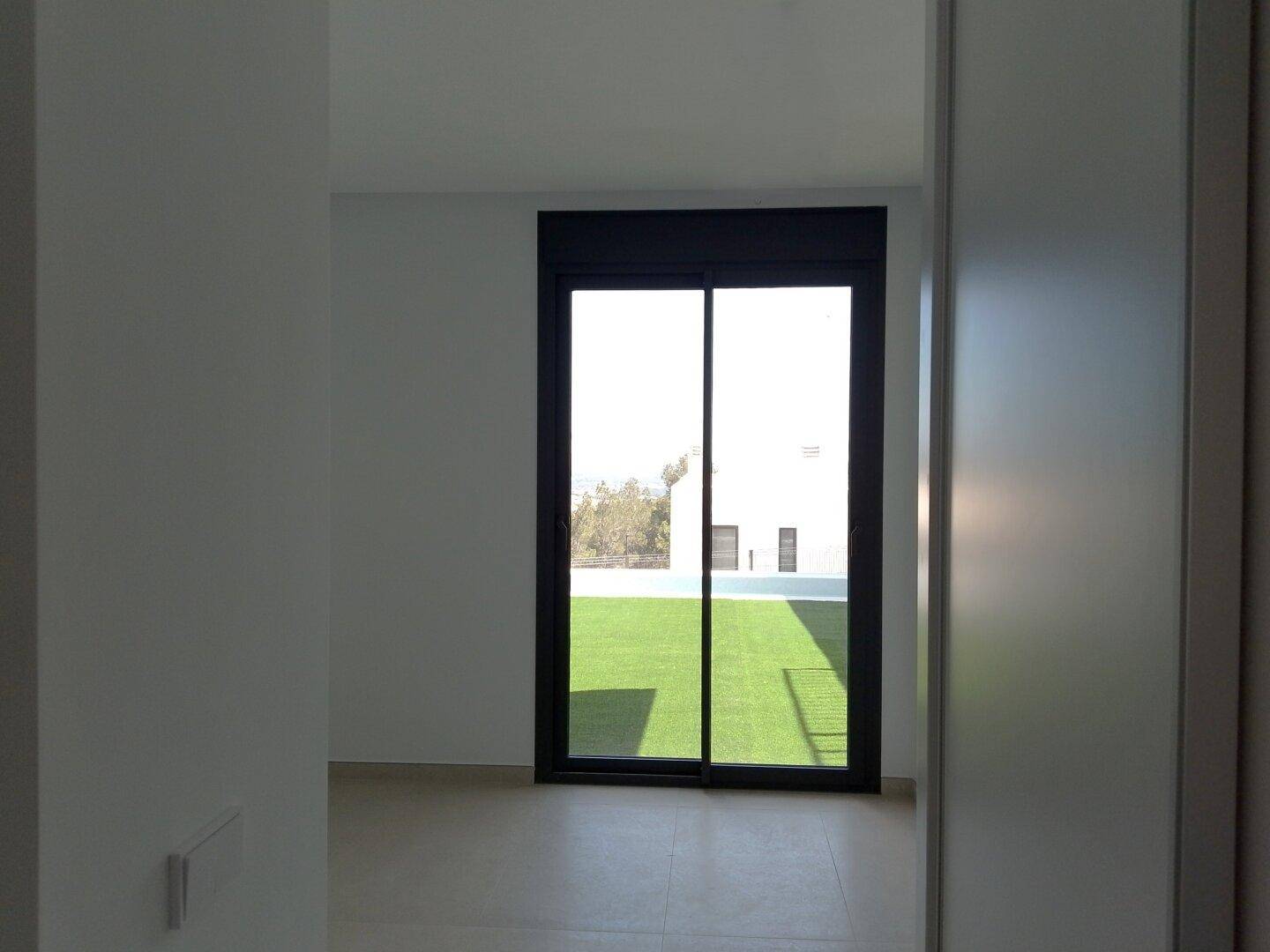 Schlafzimmer mit Schiebetür und Blick auf den grünen Außenbereich des Hauses.