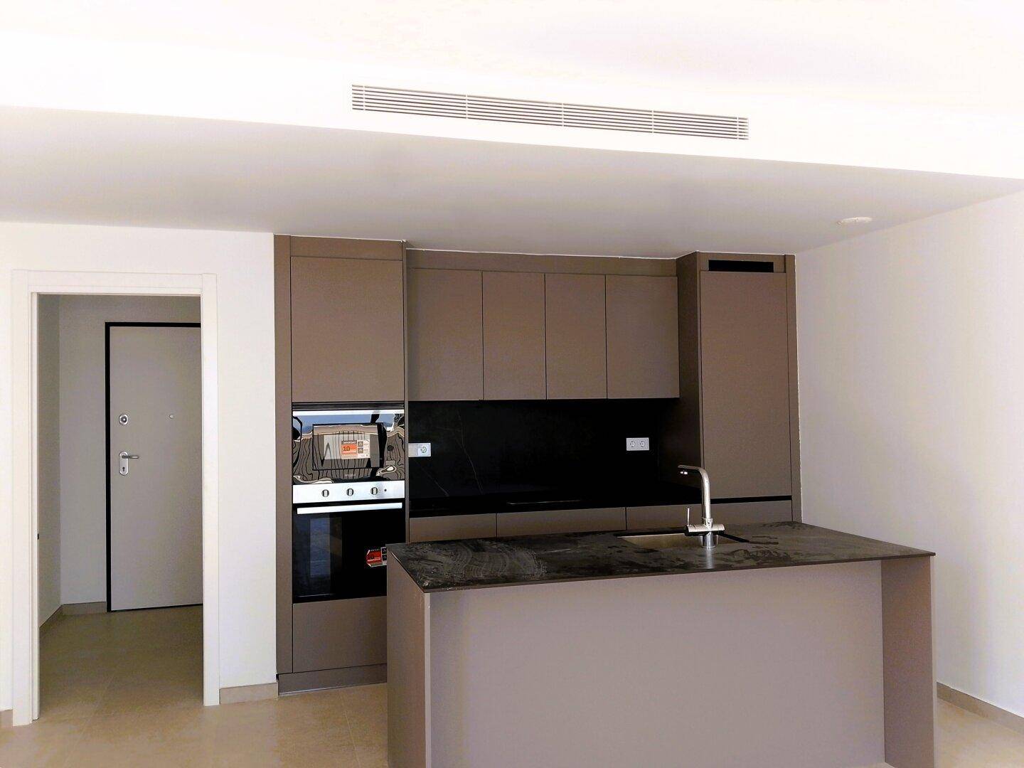 Moderne Einbauküche mit Kücheninsel, dunklen Arbeitsplatten und integrierten Geräten.