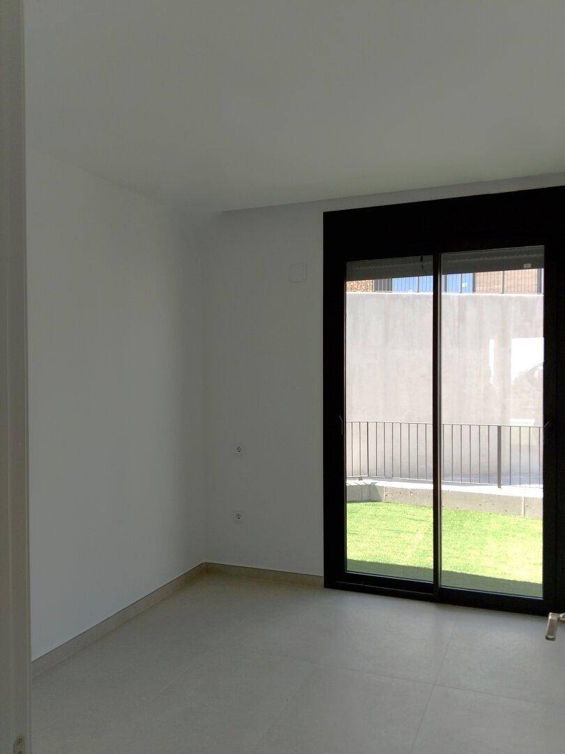Helles Schlafzimmer mit großen Fenstern und Blick auf den Außenbereich.