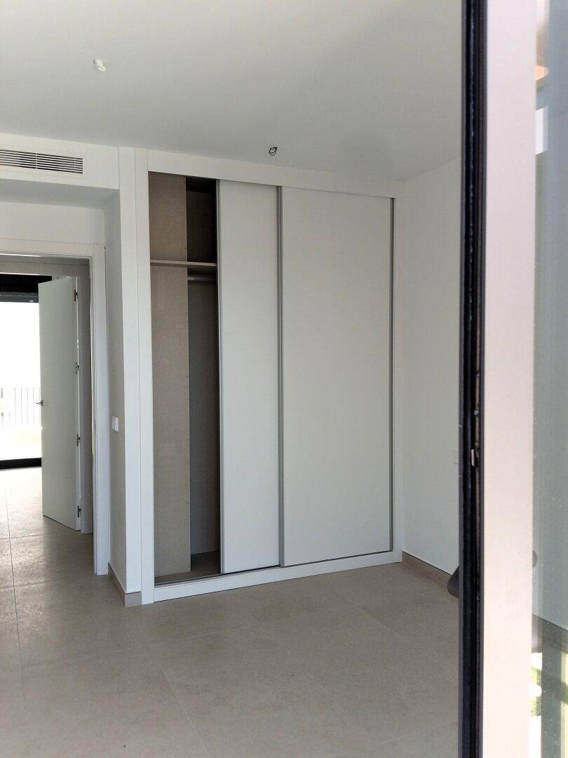 Schlafzimmer mit integriertem Schiebetürenschrank und hellem Fliesenboden.
