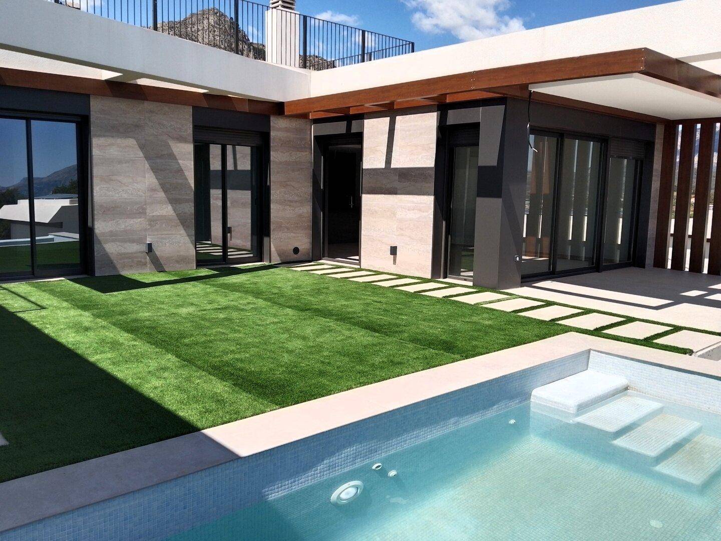 Außenbereich mit Pool, Kunstrasen und Zugang zu den Innenräumen des modernen Hauses.