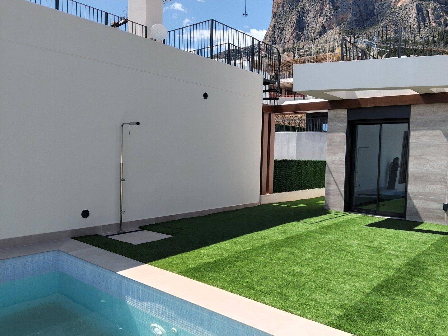 Sonniger Außenbereich mit Pool, Kunstrasen und Außendusche.