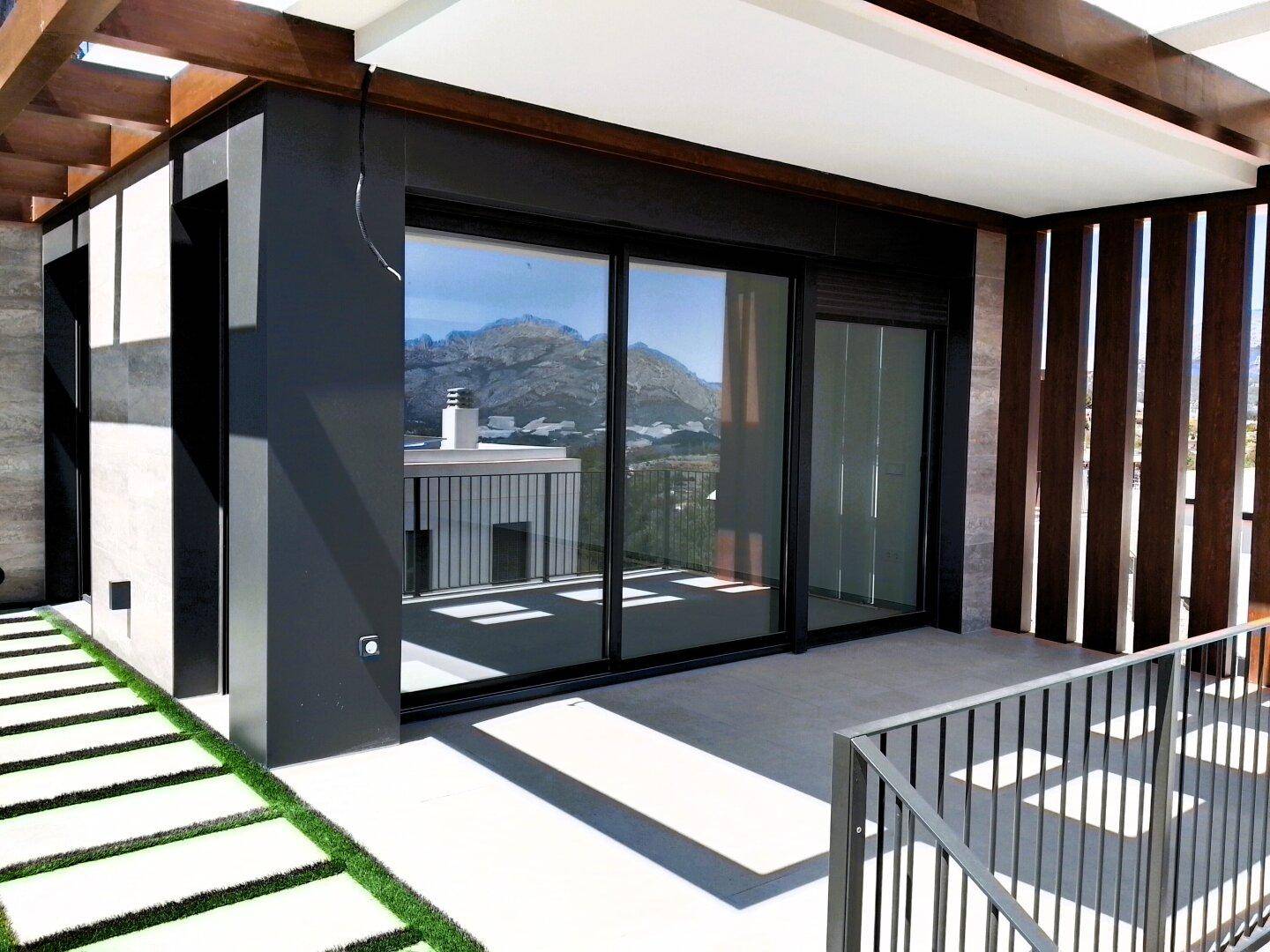 Überdachter Terrassenbereich mit modernen Schiebetüren und Blick auf die Berge.