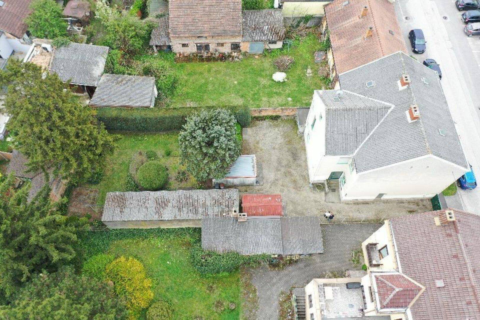 Luftaufnahme des hinteren Bereichs des Gebäudes mit Garten, Bäumen und Nebengebäuden.