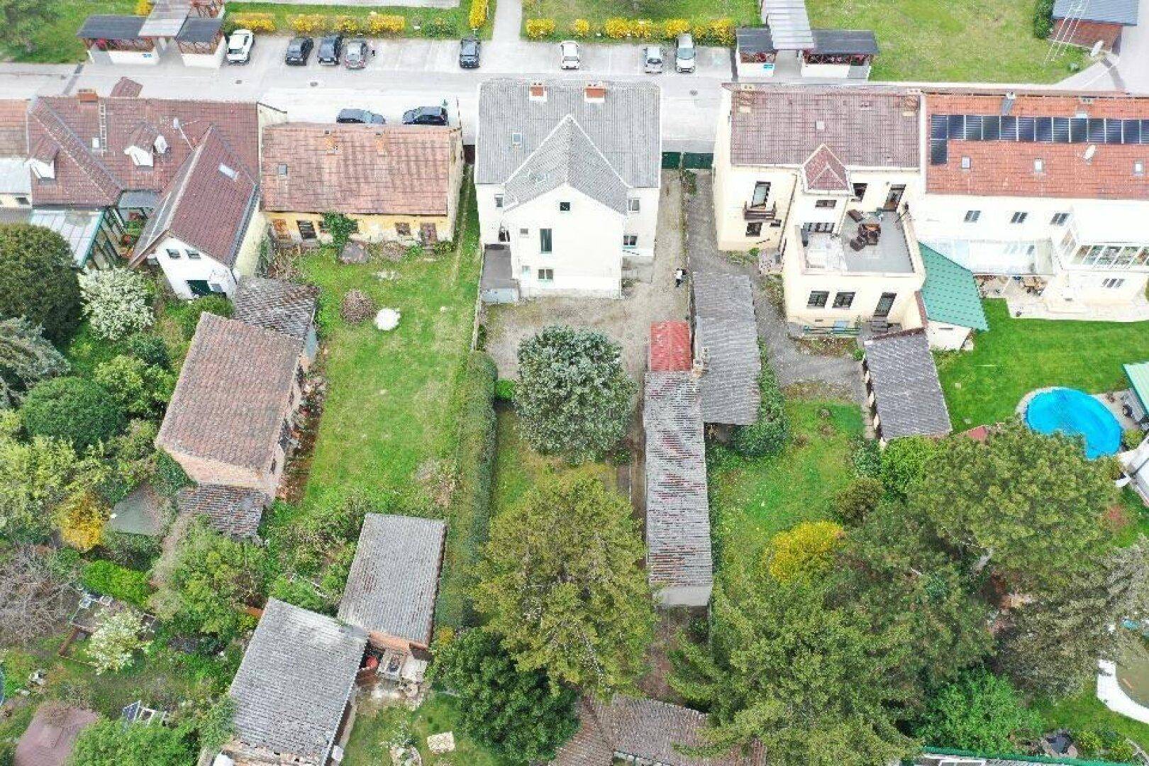 Gesamtansicht des Grundstücks von oben mit dem Gebäude, Garten und umliegenden Häusern.