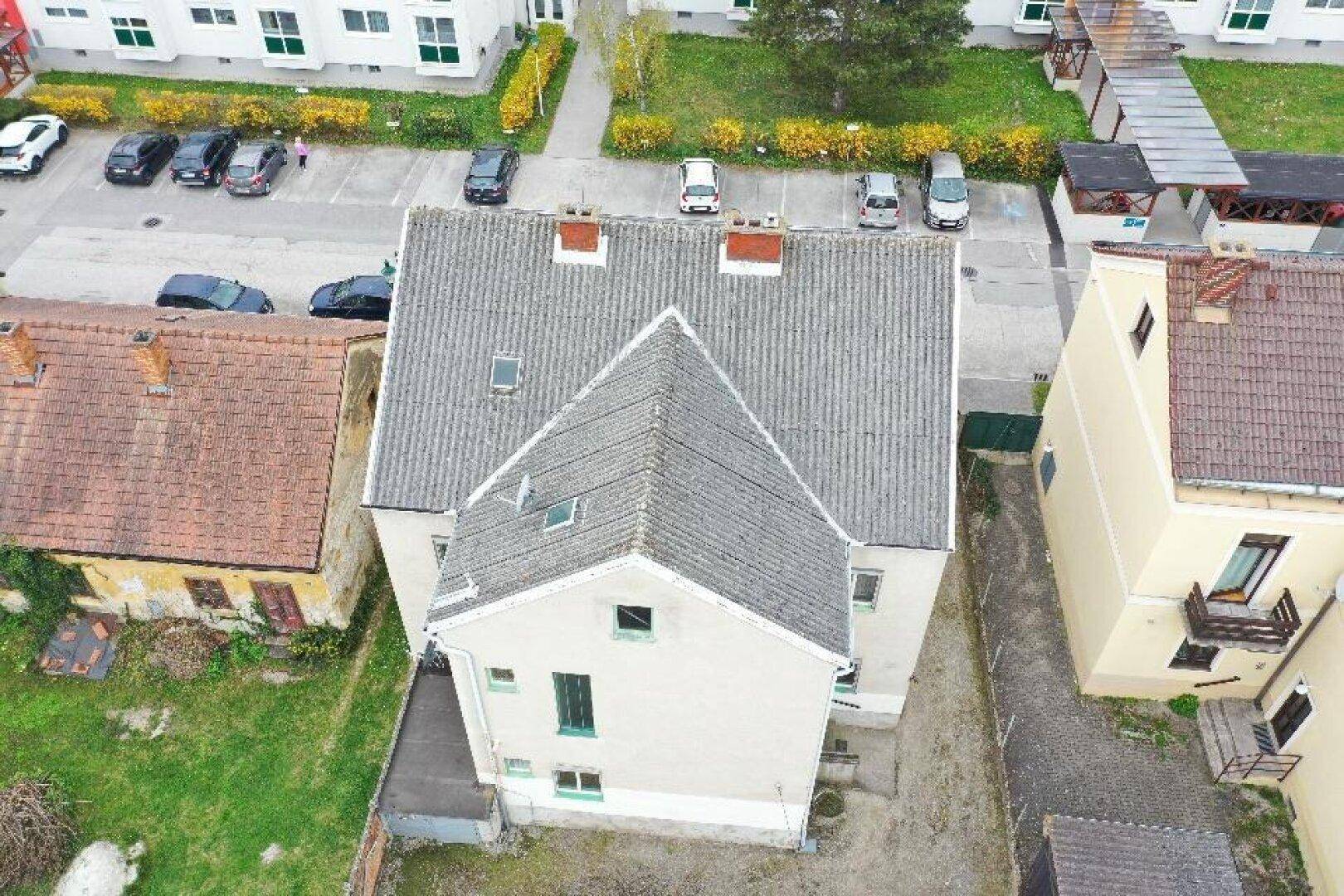 Dachansicht des Gebäudes mit Gauben und umliegenden Parkplätzen.