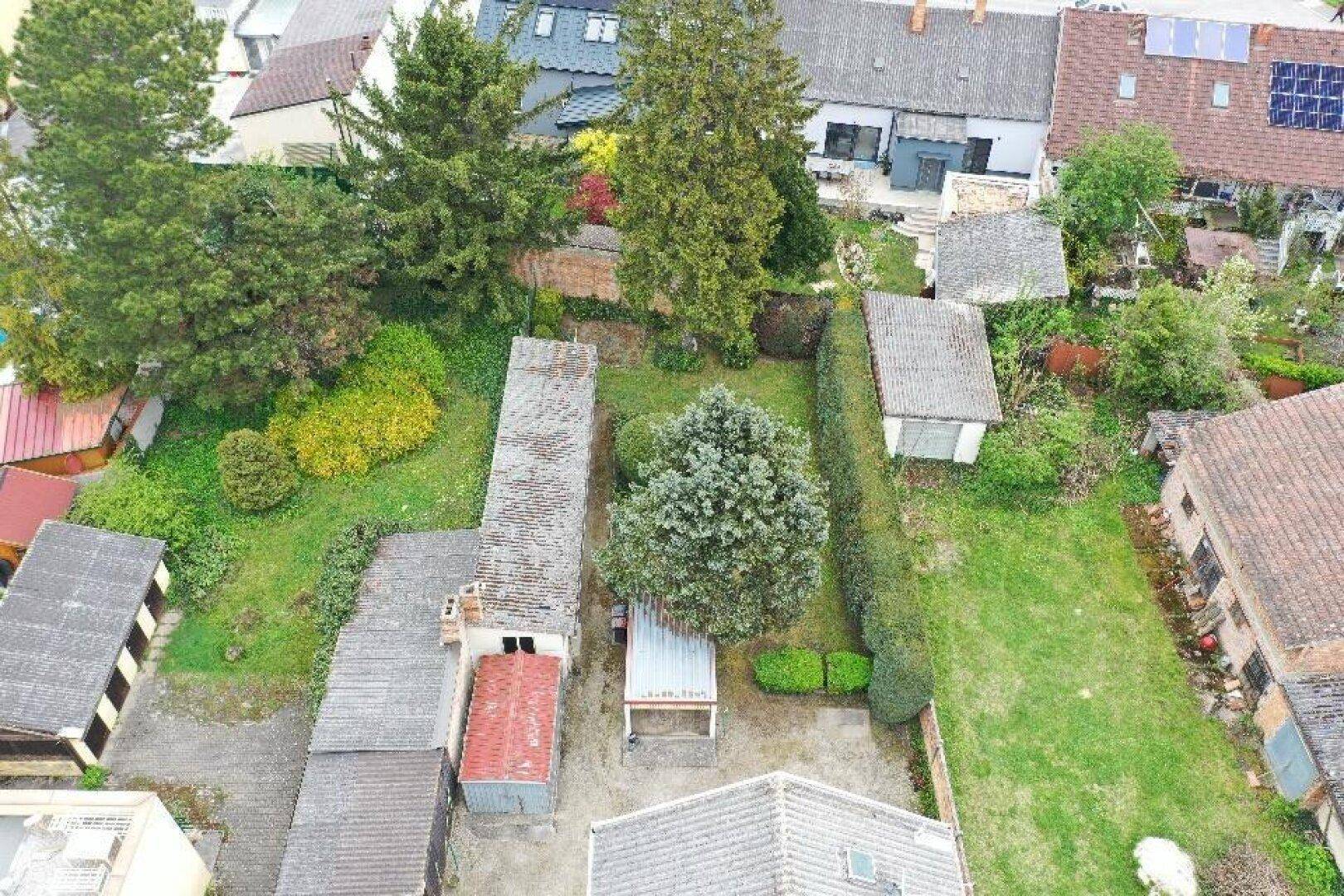Detaillierte Luftaufnahme des Gartens mit Bäumen, Hecken und mehreren Schuppen.