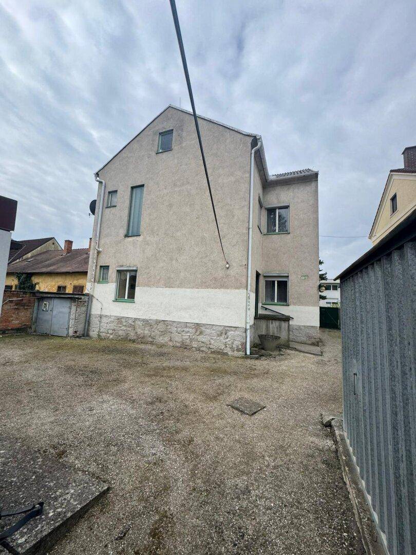 Rückansicht des Gebäudes mit einfacher Fassade und einem Schotterbereich im Vordergrund.