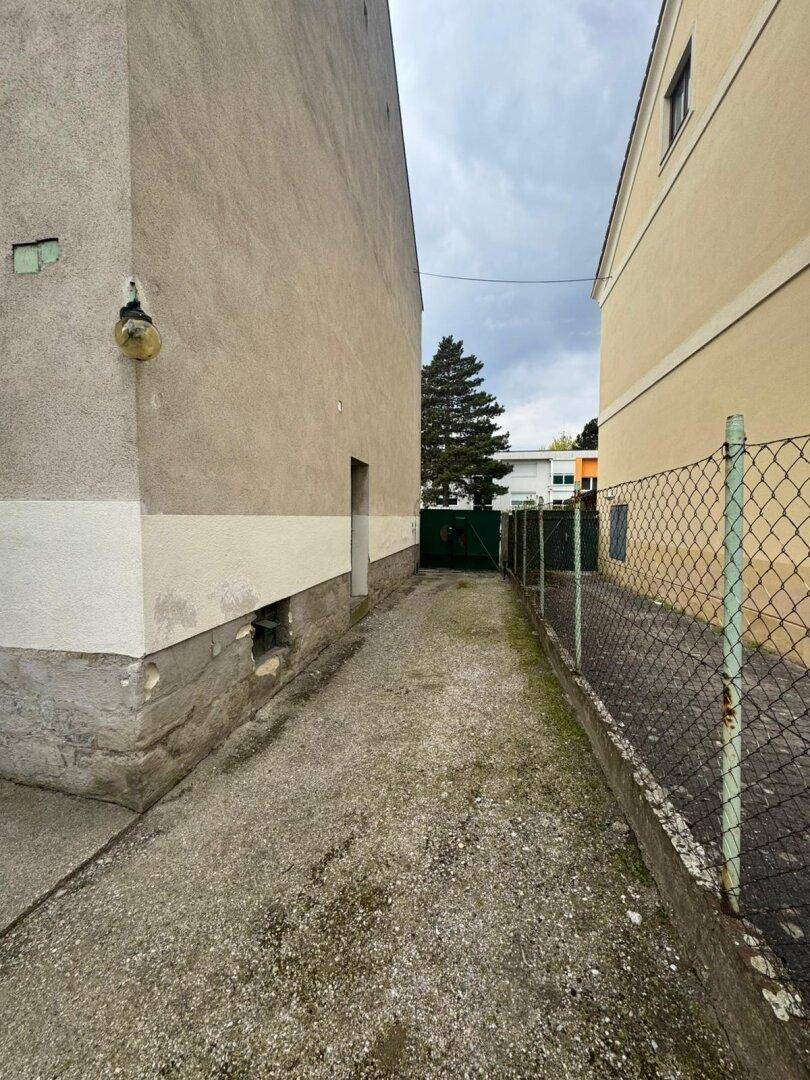 Schmaler Weg zwischen zwei Gebäuden, der zum hinteren Bereich führt.