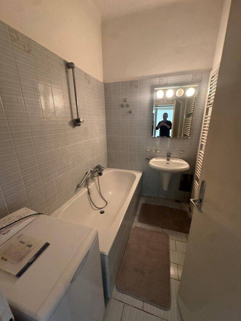 Badezimmer mit Badewanne, Waschbecken und Wandfliesen in hellem Blau.