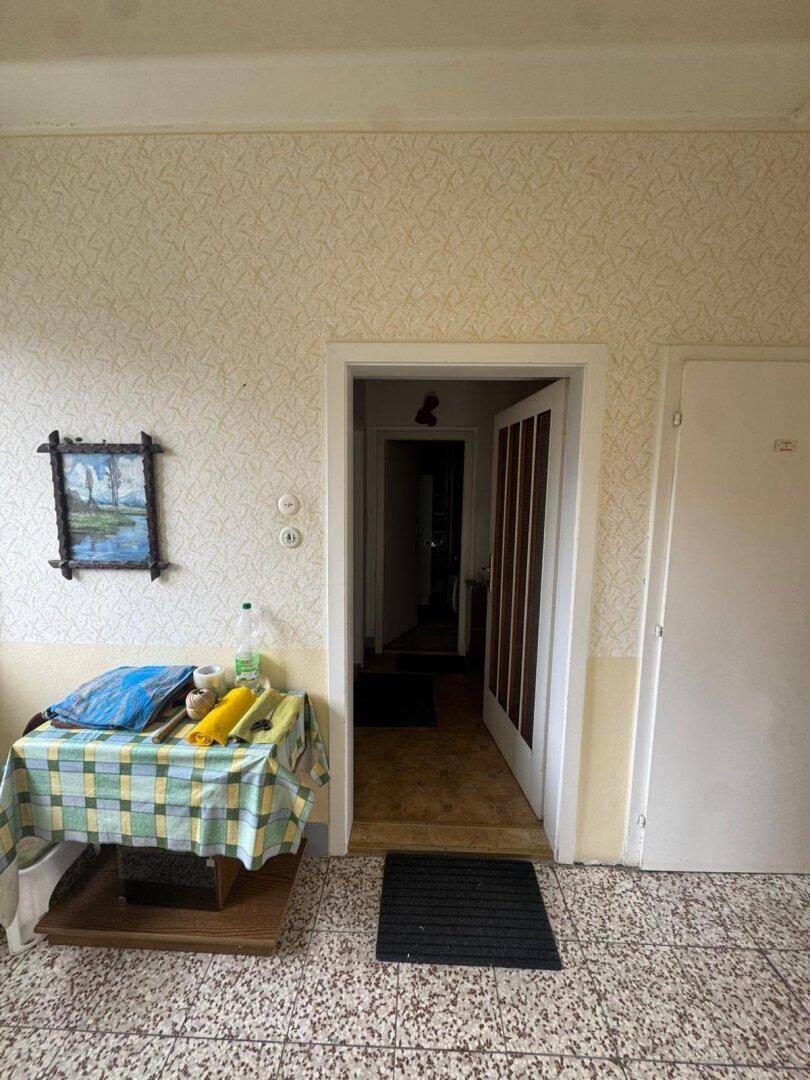 Flur mit gemusterter Tapete und einem kleinen Tisch mit Dekoration.