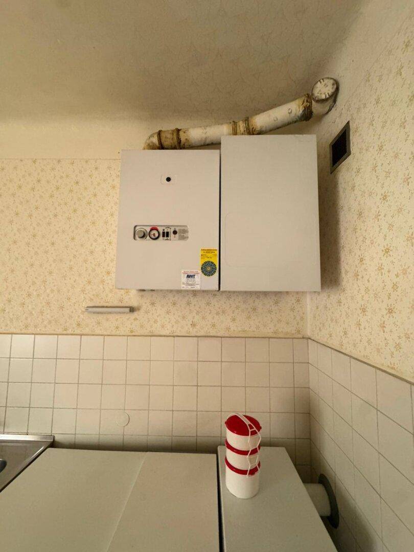 Nahaufnahme einer Gastherme an der Wand über den Küchenfliesen.