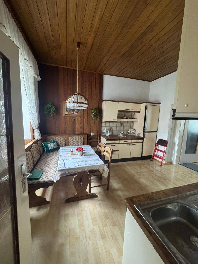 Traditionelle Wohnküche mit Holztäfelung, Eckbank und Blick auf den Essbereich.