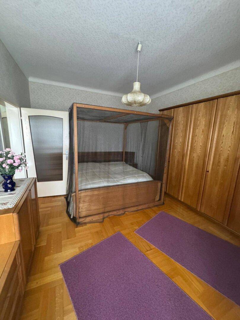 Schlafzimmer mit Holzboden, Himmelbett und großen Holzschränken.