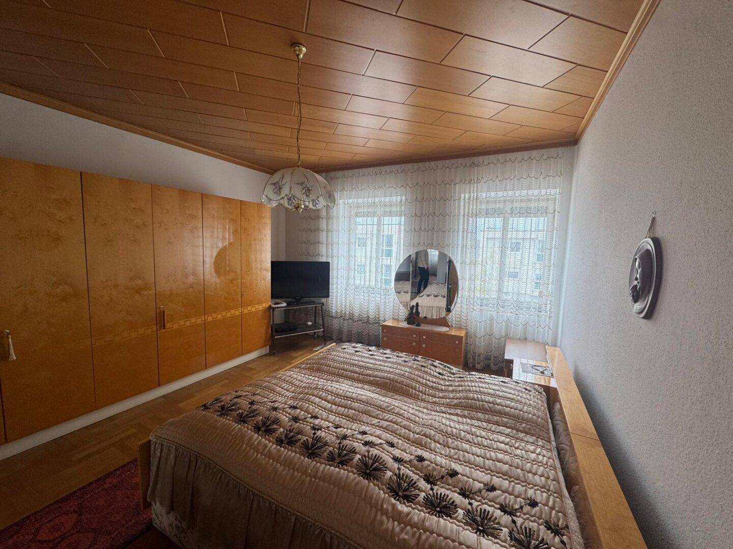 Schlafzimmer mit Doppelbett, Holzschränken und Holzdecke, bietet eine gemütliche Atmosphäre.