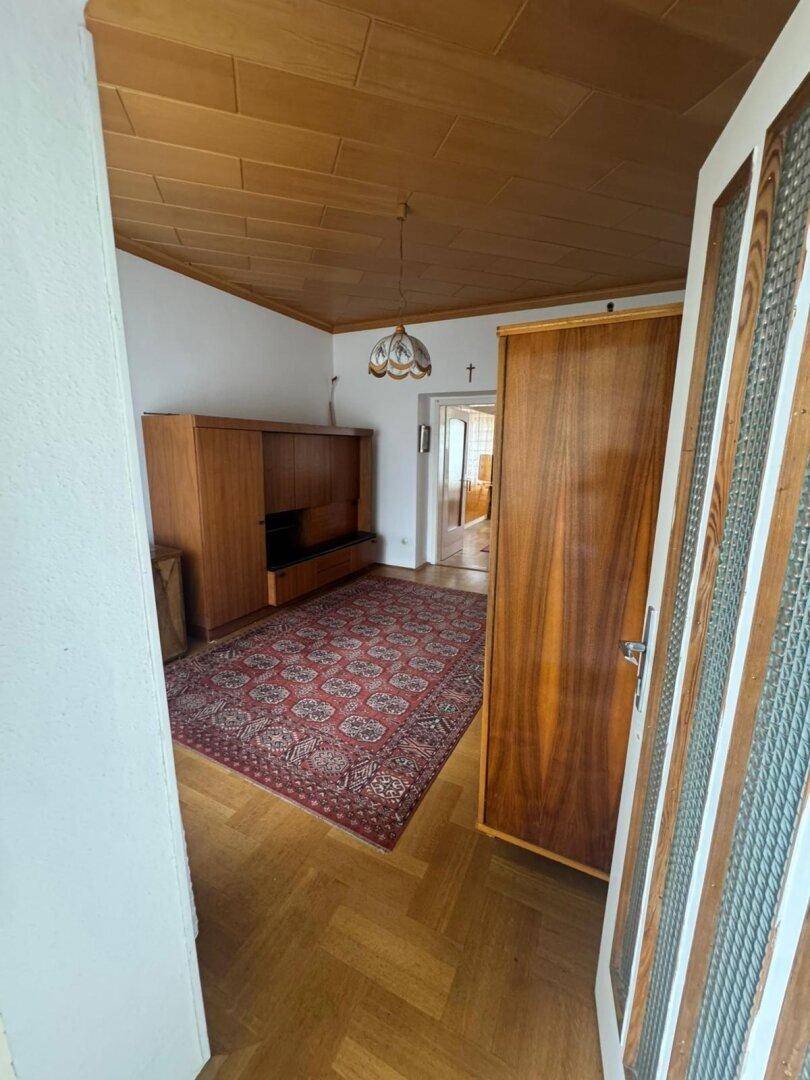 Zimmer mit Parkettboden, Holzschrank und Teppich, bietet vielseitige Nutzungsmöglichkeiten.