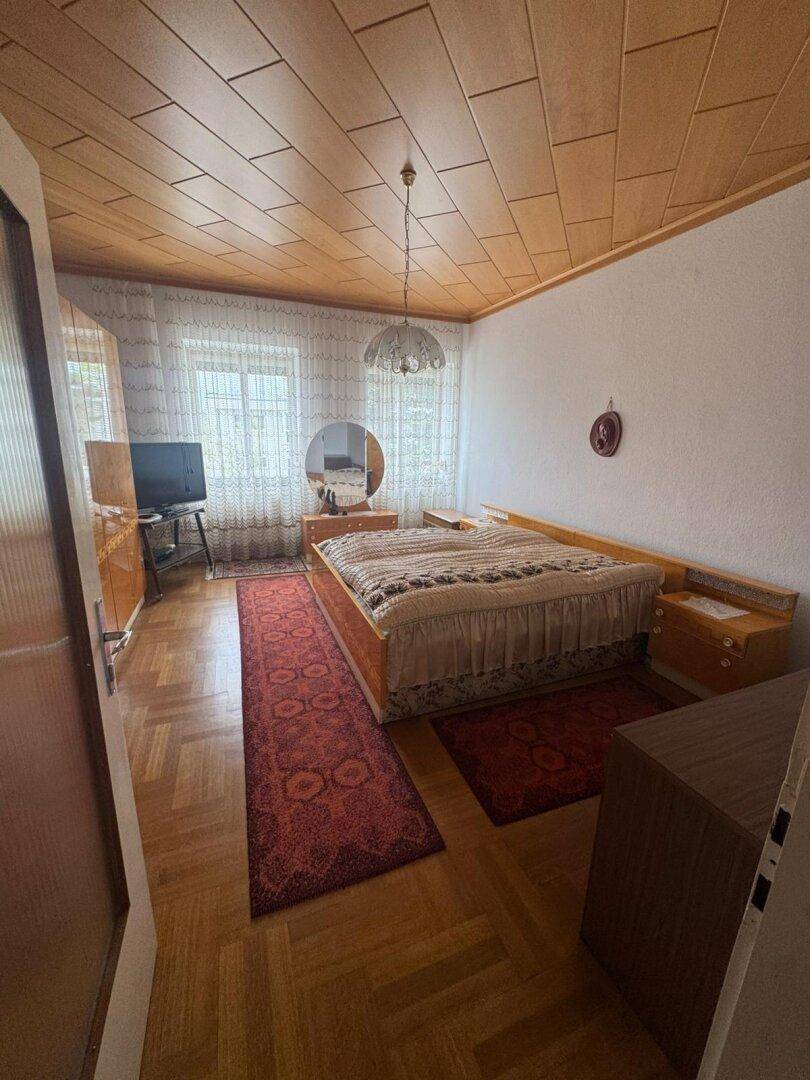 Schlafzimmer mit Doppelbett, Holzdecke und Parkettboden, traditionell eingerichtet.