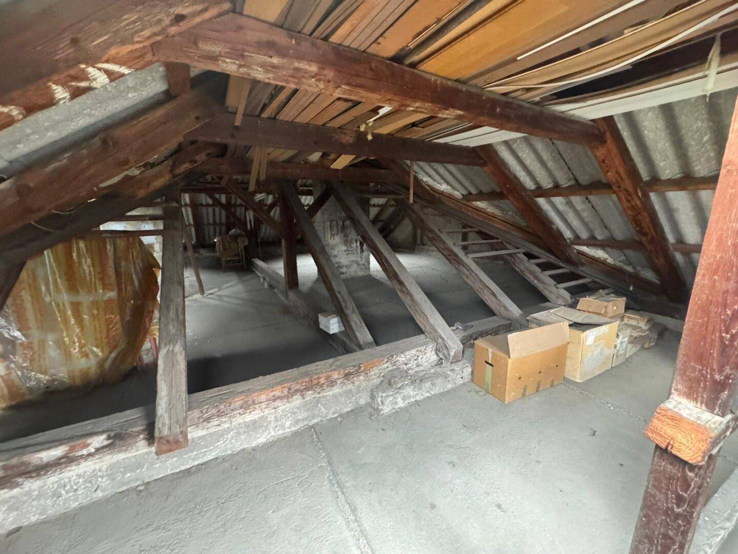 Weitläufiger, ungenutzter Dachbodenbereich mit zahlreichen freiliegenden Holzbalken und viel Platz.