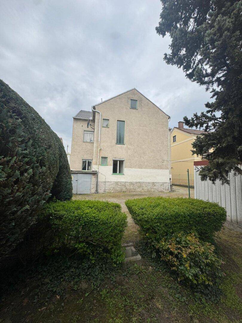 Rückansicht des Gebäudes vom Garten aus, mit schlichter Fassade und mehreren Fenstern.