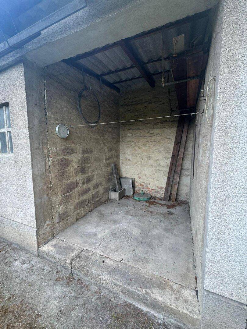 Offener Schuppenbereich mit rauen Ziegelwänden und Betonboden, ideal als Lagerfläche.