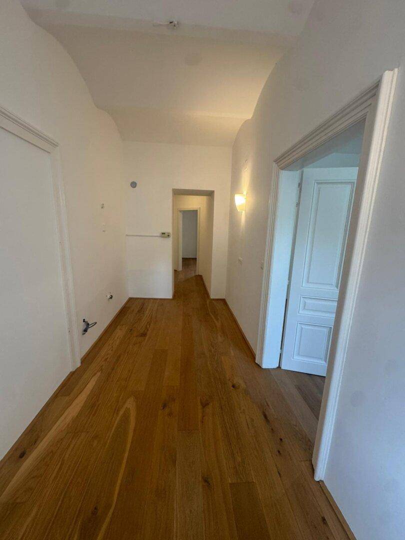Langer Flur mit elegantem Hartholzboden, der verschiedene Zimmer der Wohnung miteinander verbindet.