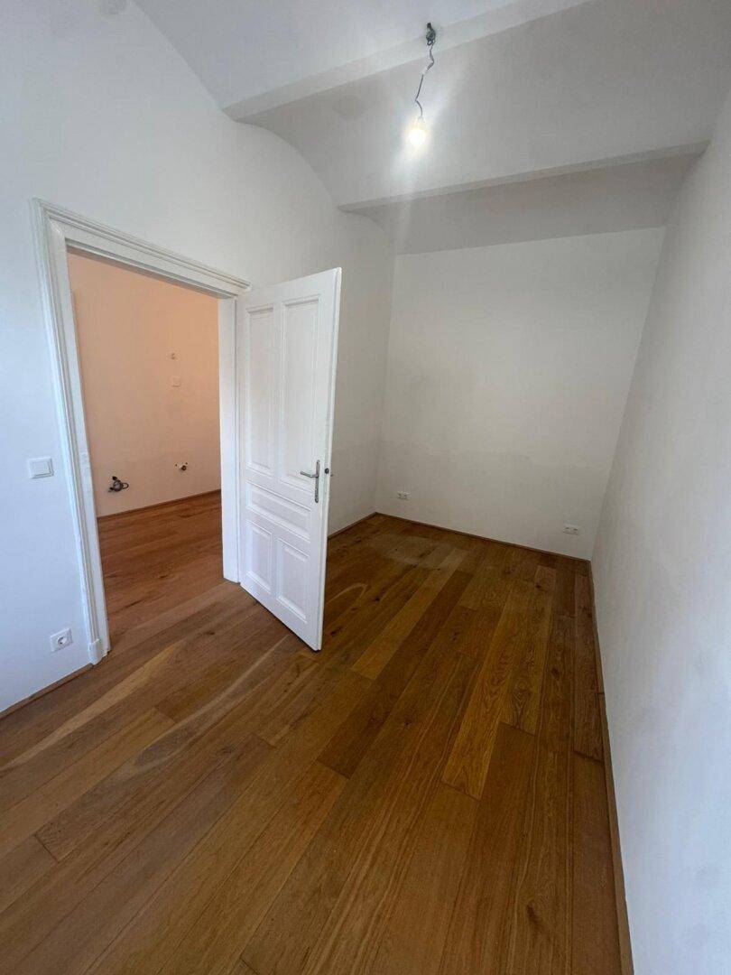 Gemütliches Zimmer mit Hartholzboden und weiß gestrichenen Wänden, ideal als Schlaf- oder Arbeitszimmer.