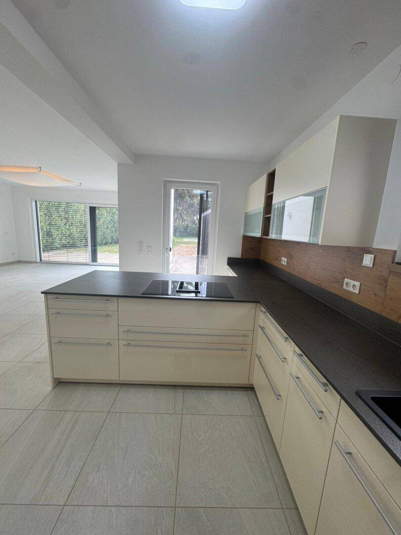 Geräumige, moderne Küche mit Kücheninsel und hellen Schränken, offen zum Wohnbereich.