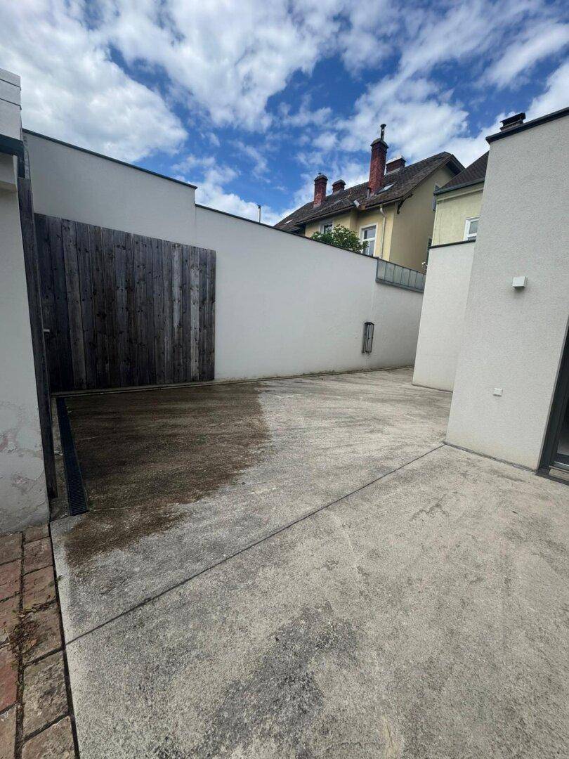 Betonierter Innenhof mit Holzzaun, der einen Teil des Grundstücks abgrenzt.