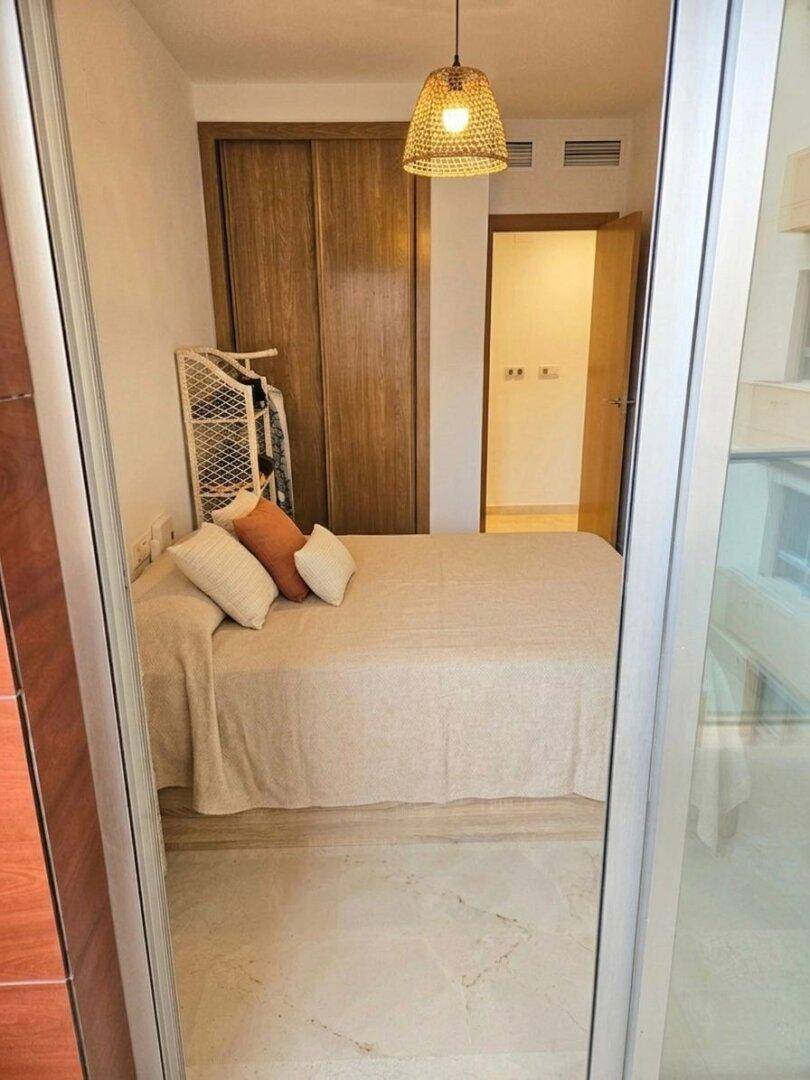 Schlafzimmer mit Doppelbett, Einbauschrank und gefliestem Boden, durch eine Tür zugänglich.