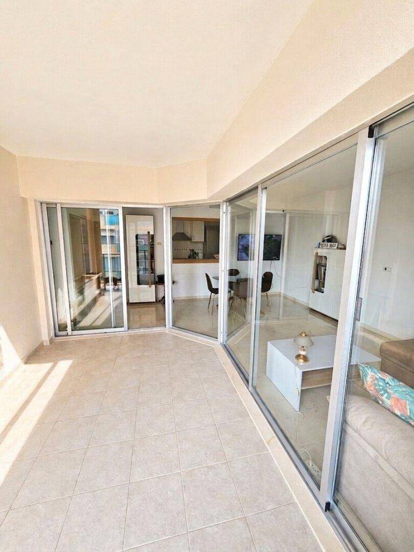 Heller, verglaster Balkon mit Fliesenboden und Blick in den offenen Wohnbereich der Wohnung.