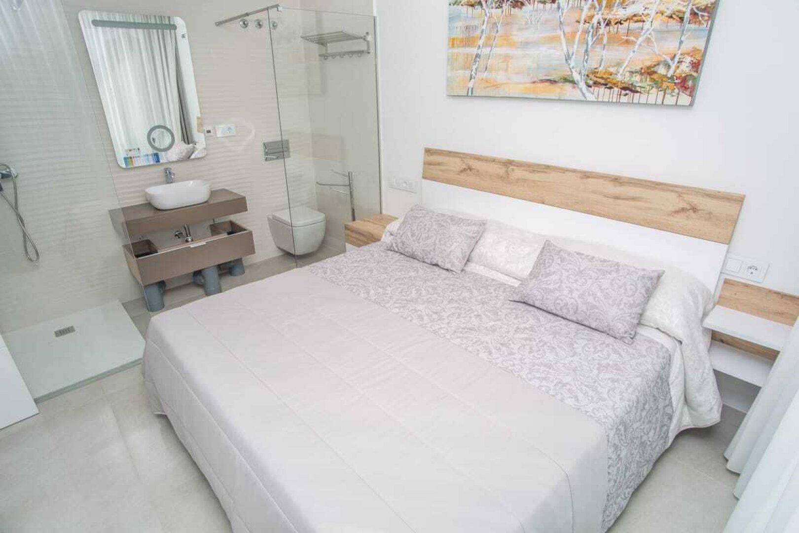 Modernes Schlafzimmer mit integriertem Badbereich, Dusche und stilvollem Waschbecken.