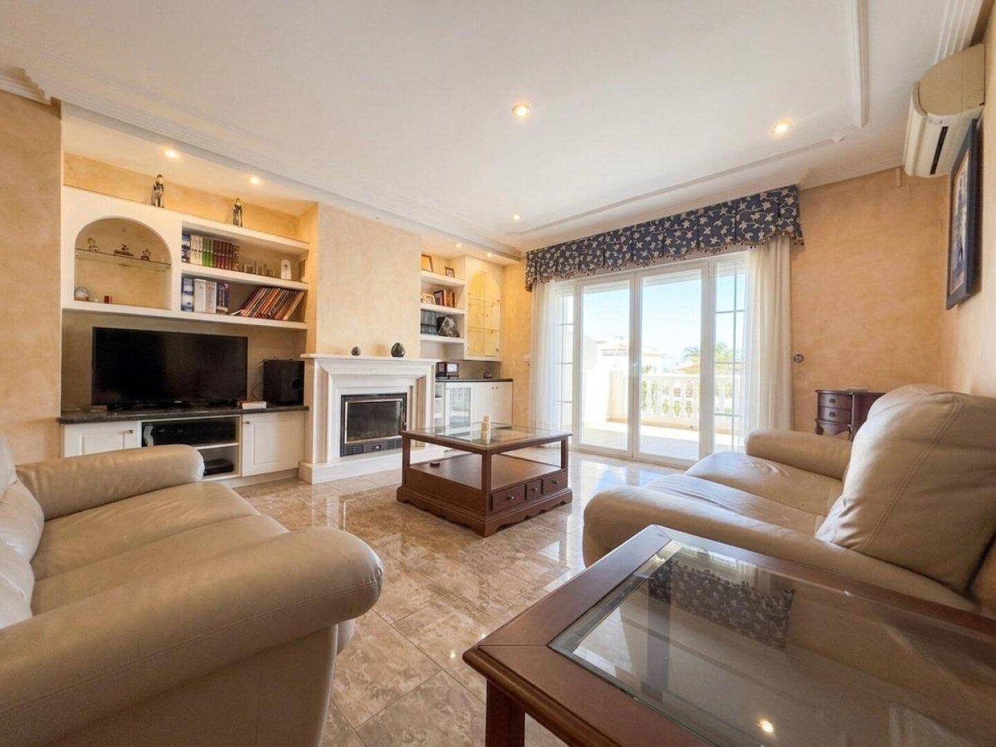 Helles Wohnzimmer mit bequemen Sofas, Kamin und Zugang zu einem sonnigen Balkon.