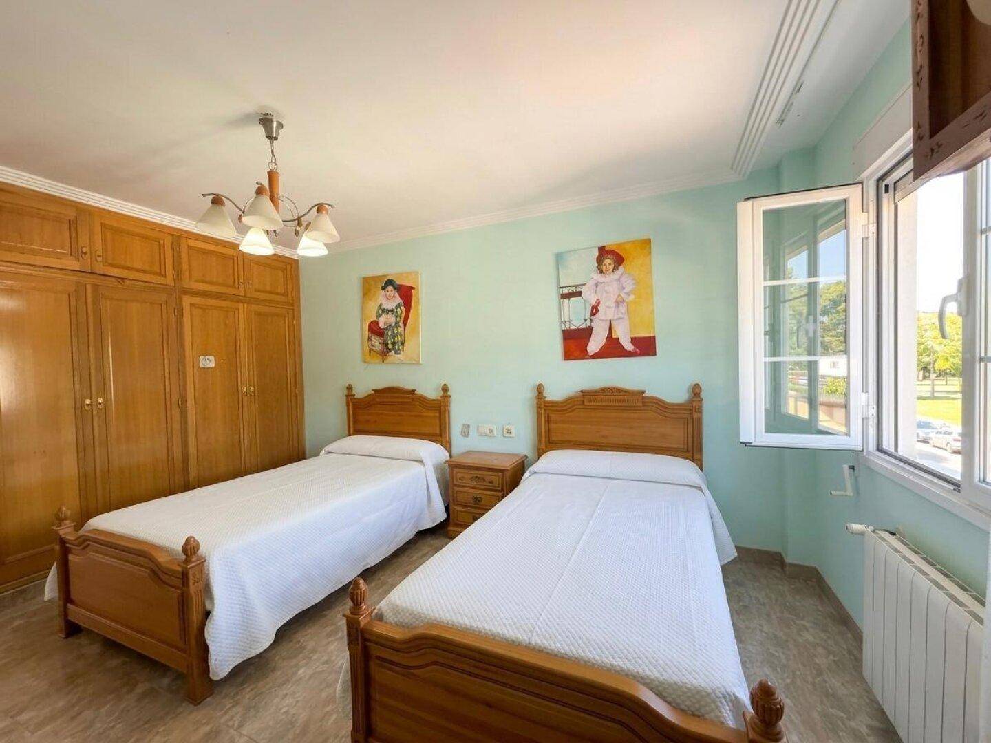 Helles Schlafzimmer mit zwei Einzelbetten und einem großen Einbauschrank.