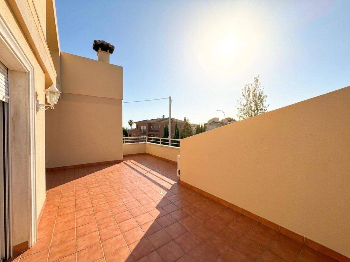 Sonnige Dachterrasse mit roten Fliesen und Blick auf die Umgebung.