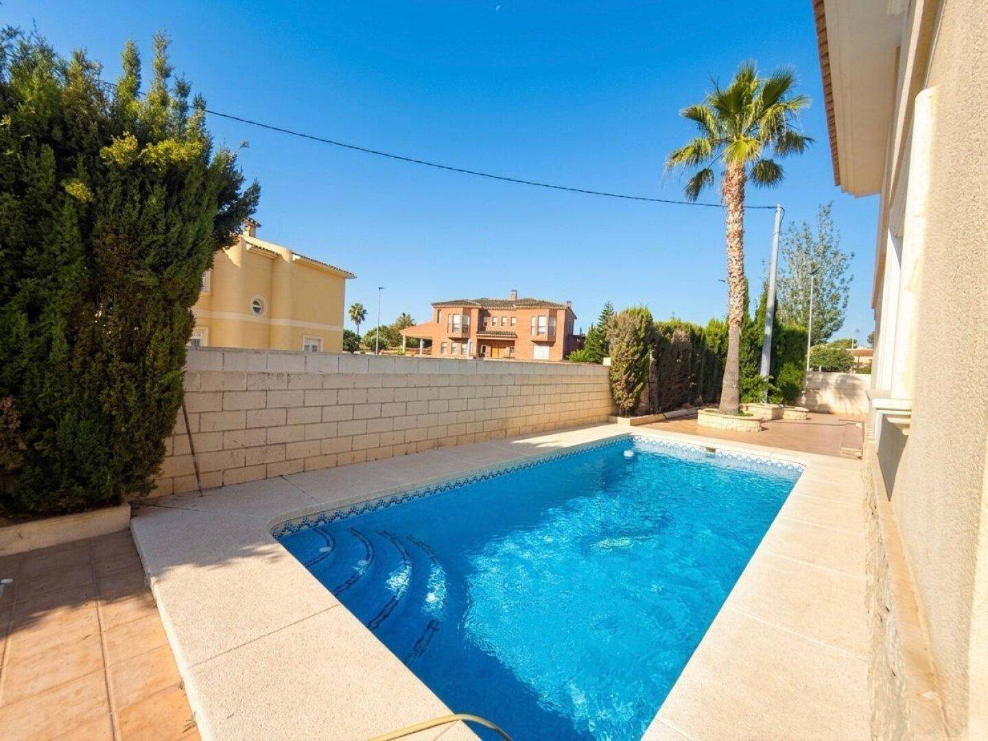 Schmaler Swimmingpool mit blauen Fliesen und gemauerter Umrandung, ideal für eine Abkühlung.