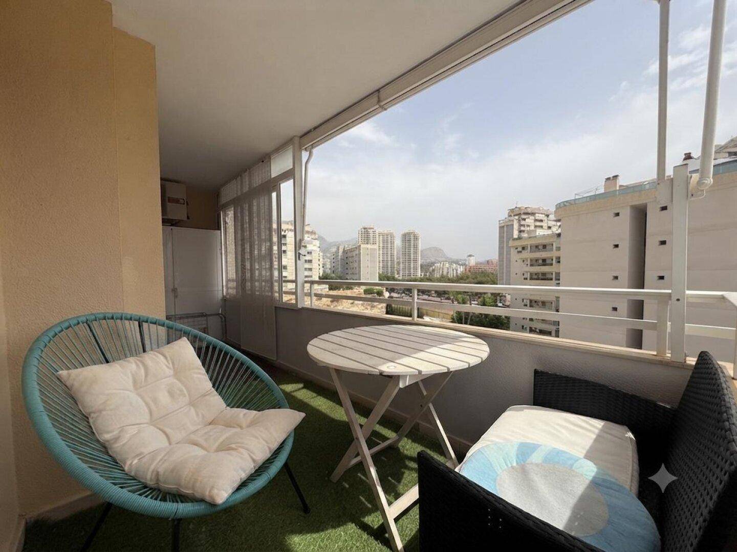 Gemütlicher Balkon mit Kunstrasen, Sitzgelegenheiten und weitem Blick über die Stadt und Berge.