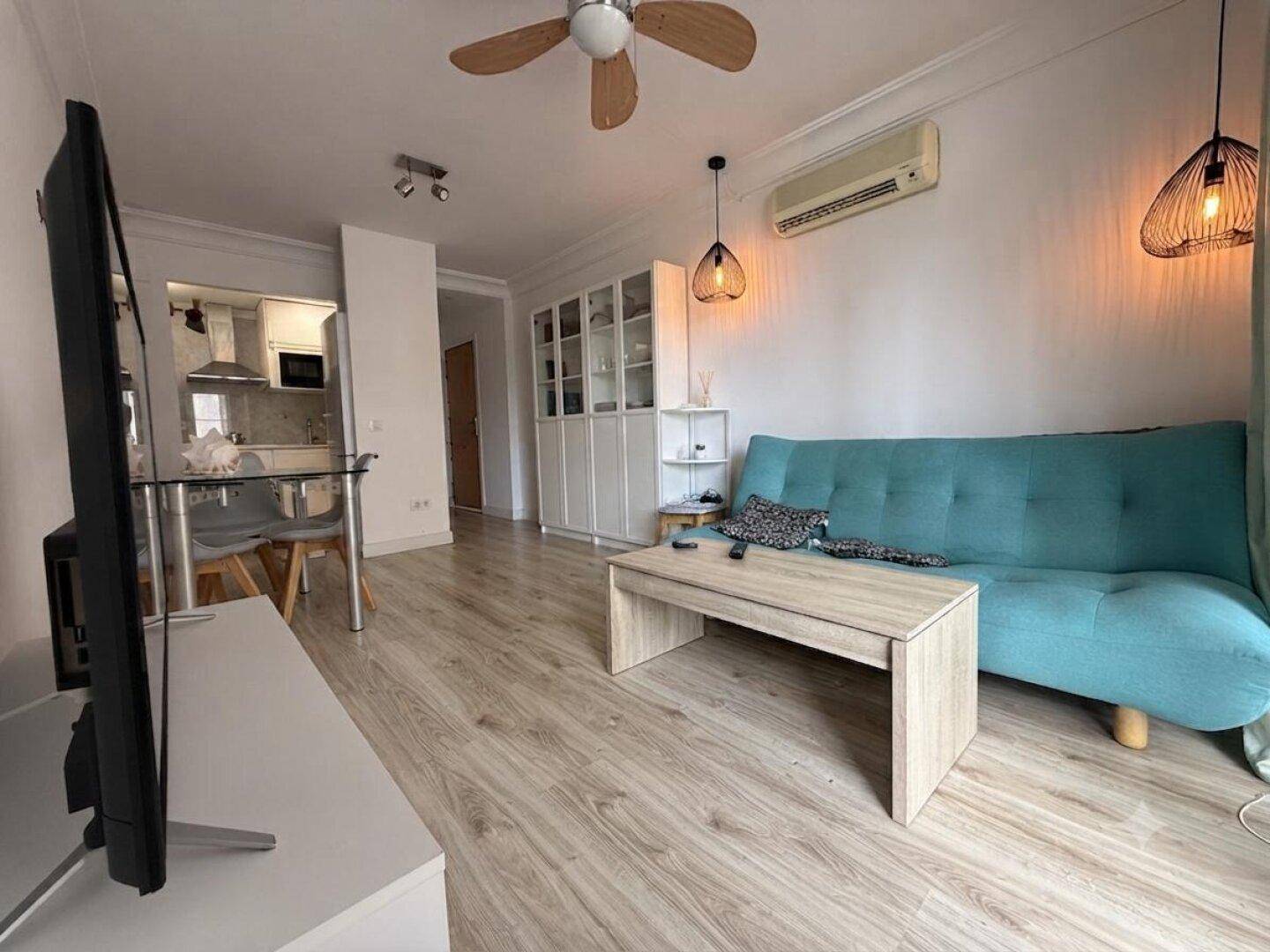Offener Wohnbereich mit Sofa, Esstisch und Blick auf die angrenzende, halboffene Küche.