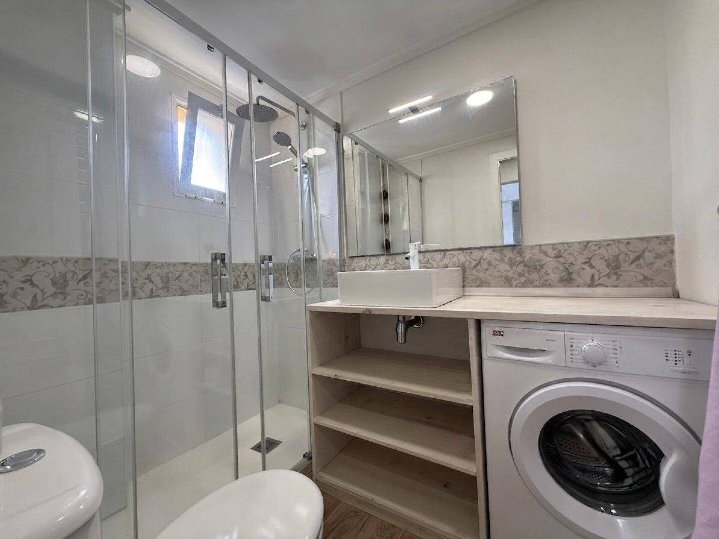 Modernes Badezimmer mit begehbarer Dusche, Waschmaschine und stilvollem Aufsatzwaschbecken.