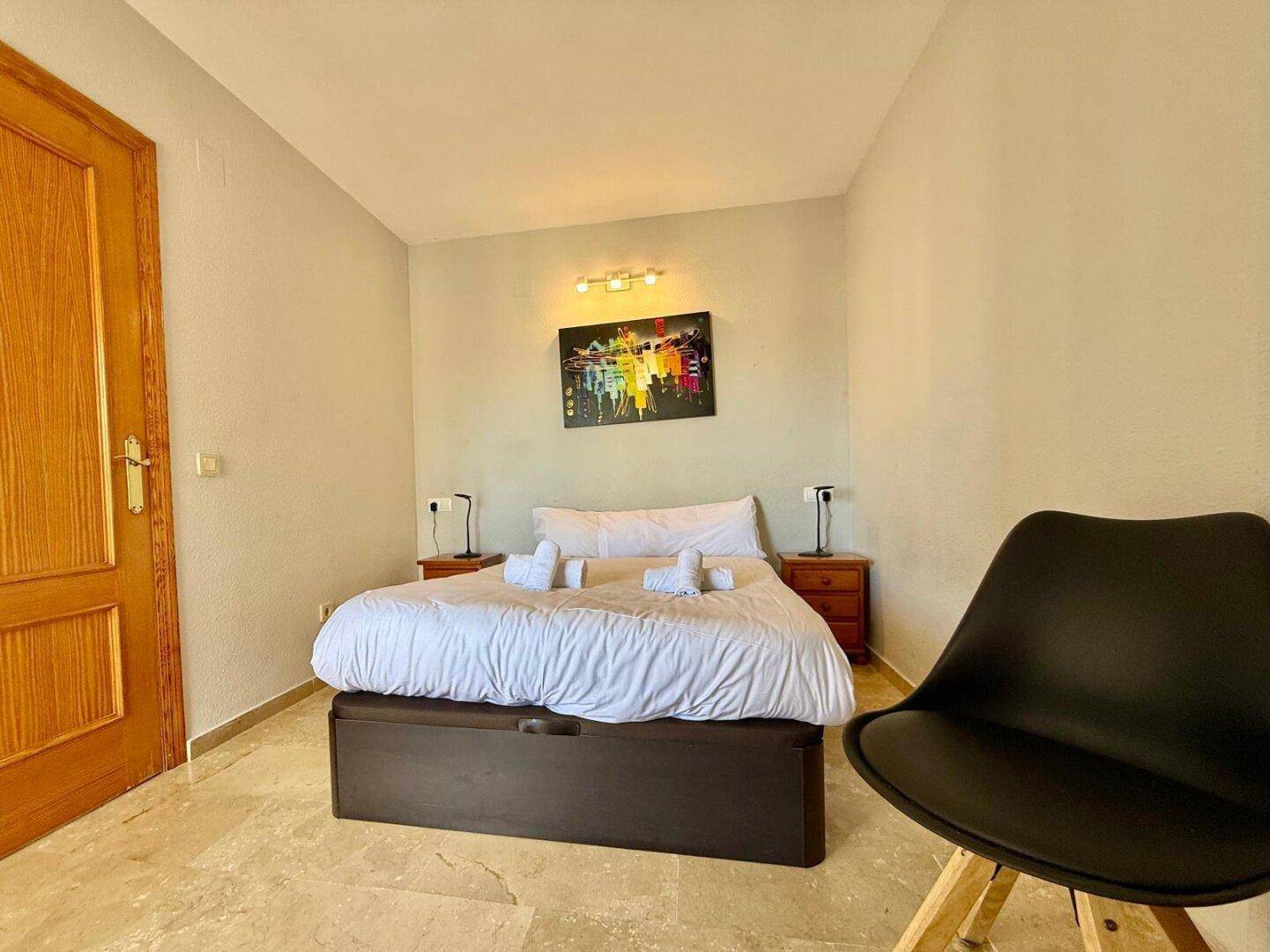 Gemütliches Schlafzimmer mit Doppelbett, Nachttischen und Holztür.