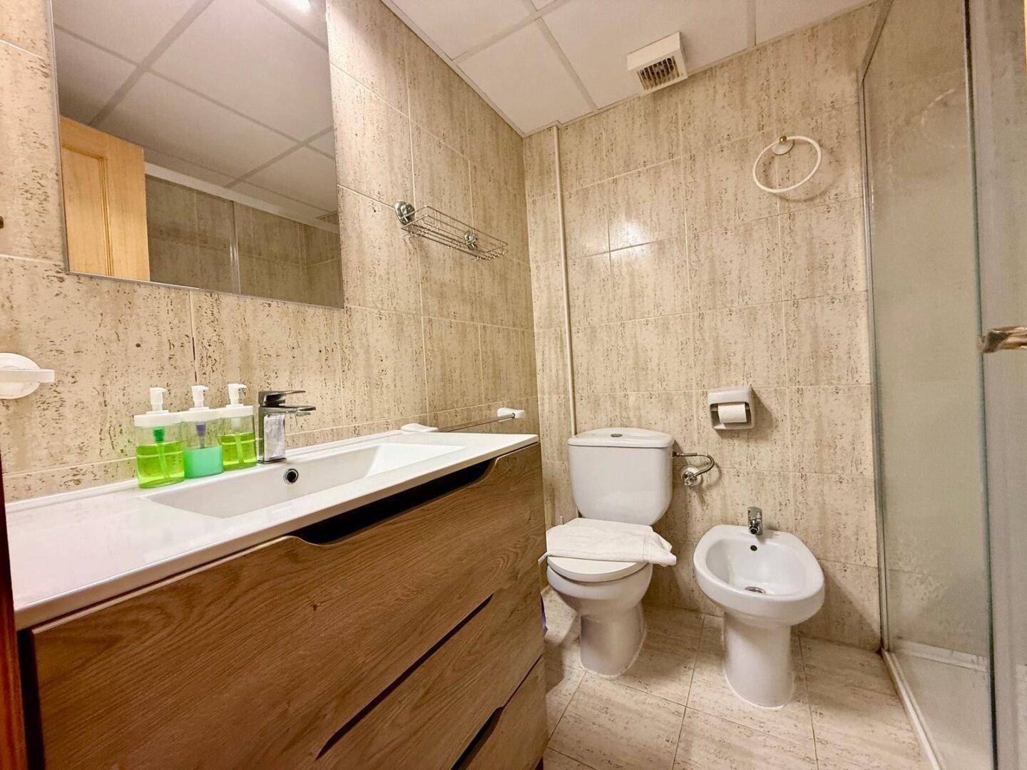 Modernes Badezimmer mit Waschtisch, Toilette, Bidet und Duschbereich.