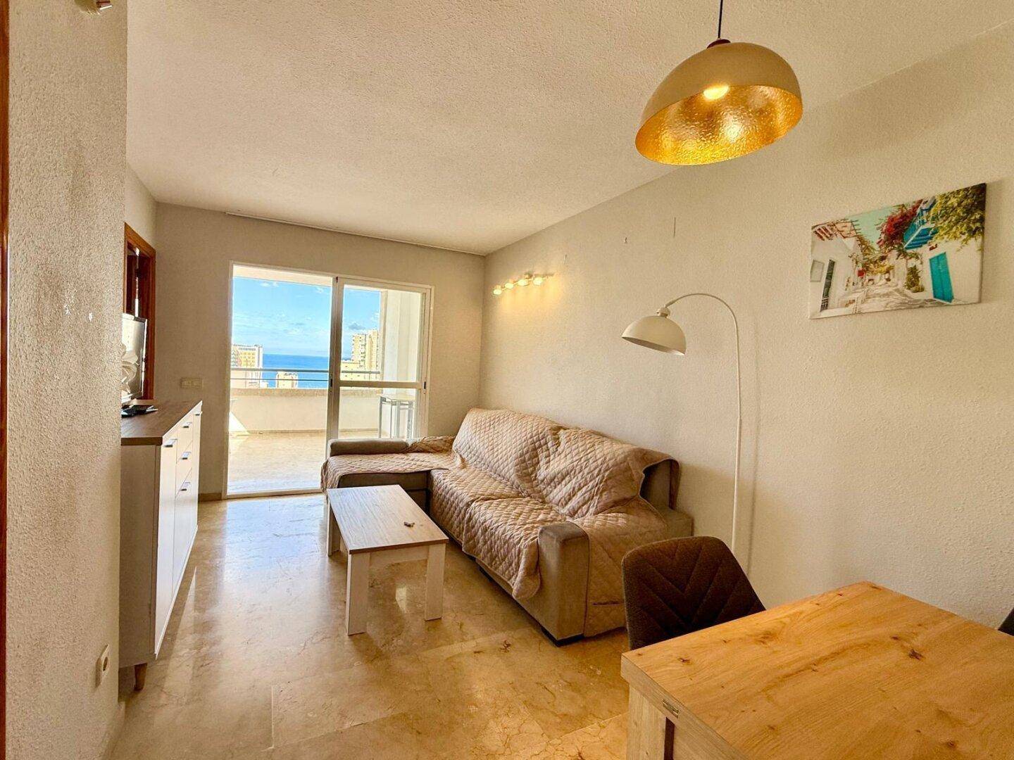 Gemütliches Wohnzimmer mit Sofa, Couchtisch und direktem Zugang zum Balkon mit Meerblick.
