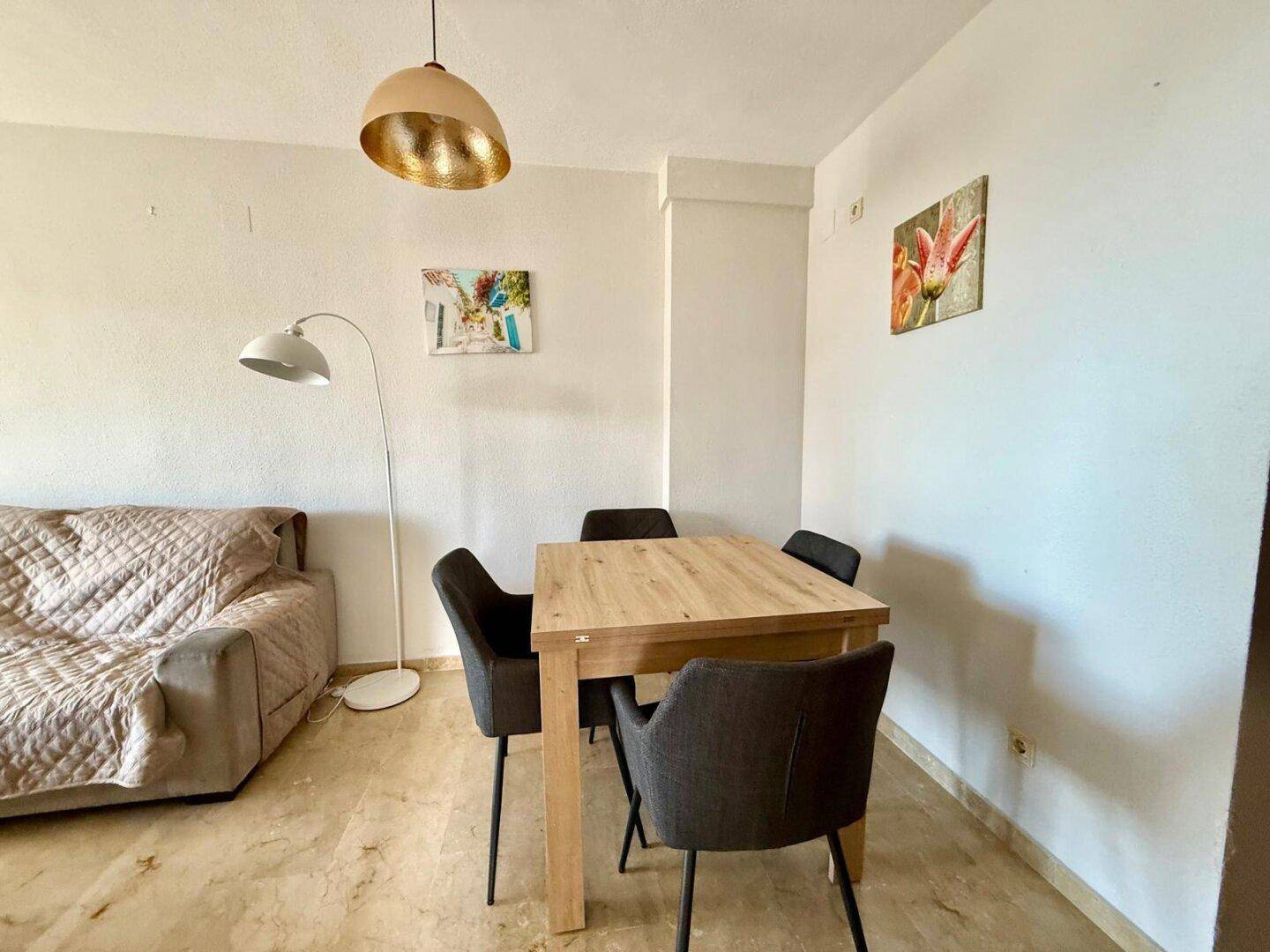 Essbereich mit modernem Holztisch und dunklen Stühlen, integriert in den Wohnraum.